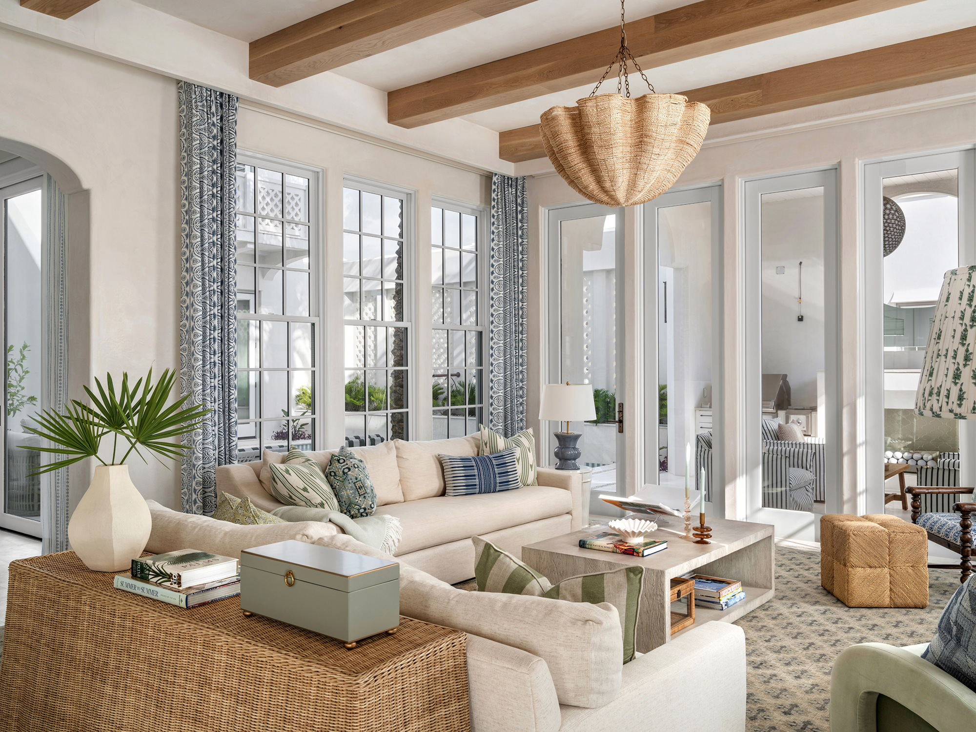 Bright living room with large windows, beige sofa, potted plant, and eclectic decor.
