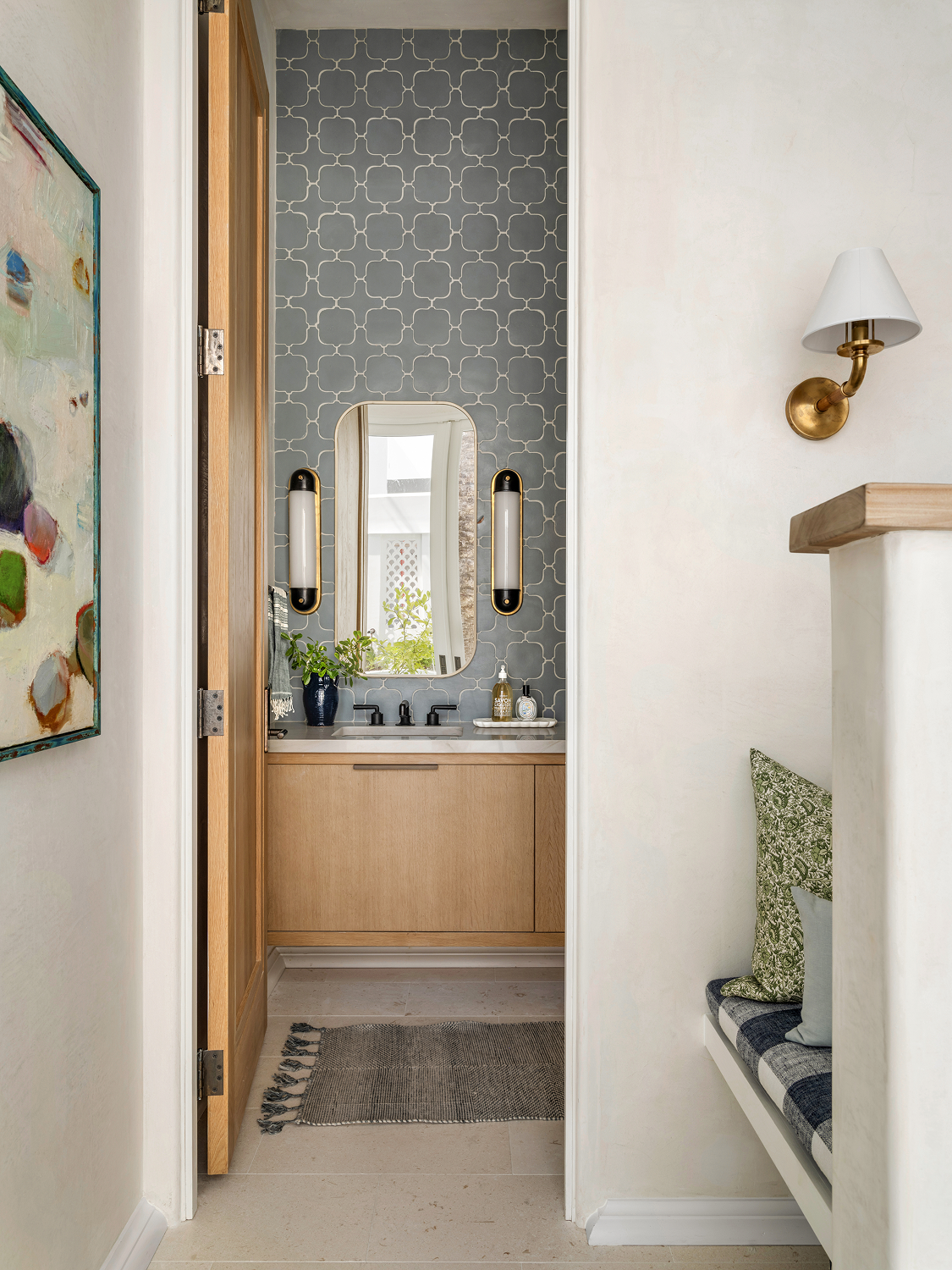 View of a modern bathroom with a wooden vanity, a mirror, and decorative wallpaper.